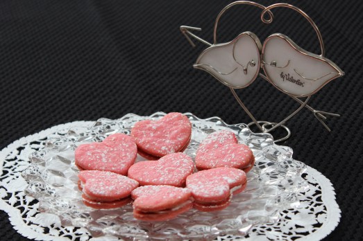 Pink heart sandwich cookies with cream filling.
