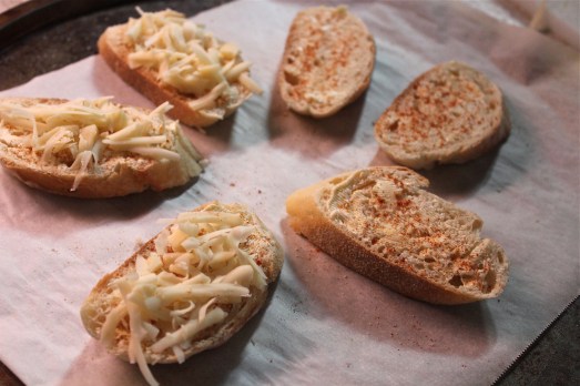 Top each bread slice with seasoned butter and cheeses.