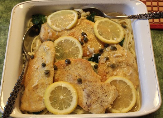 Chicken with its sauce poured over pasta with spinach.