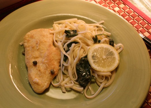 Chicken Piccata served with pasta and spinach.