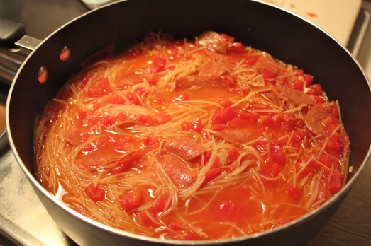 Adding in the water, wine, pasta and tomatoes.