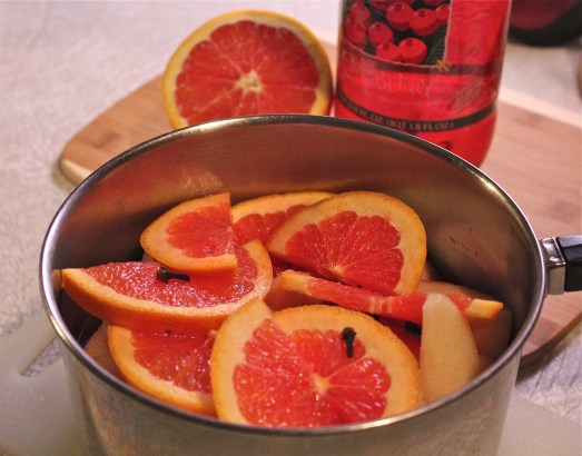 Cut-up pears, orange slices and cloves in the saucepan.